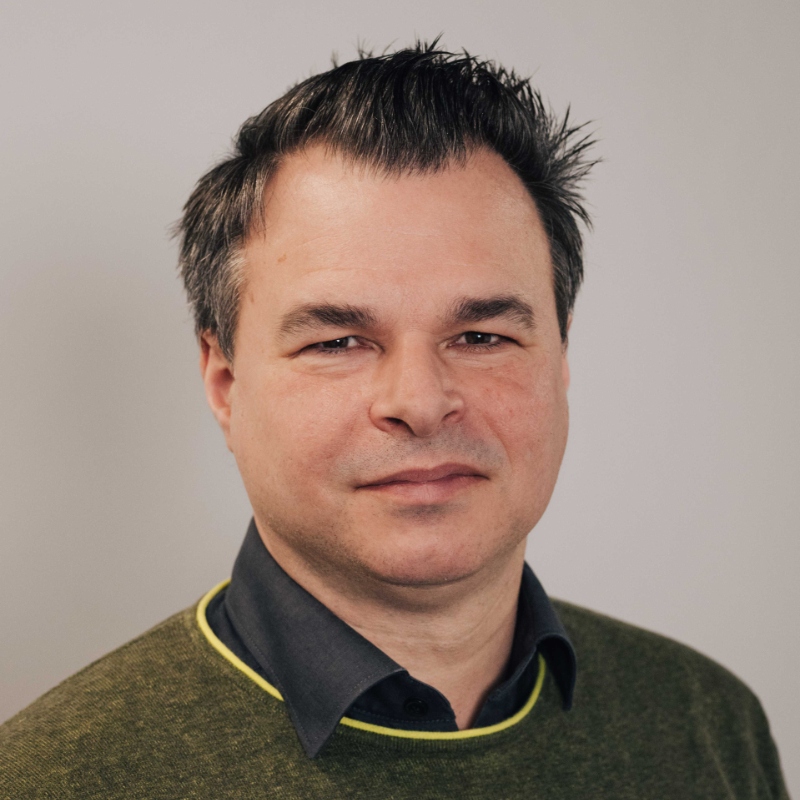 A man in front of a white wall.