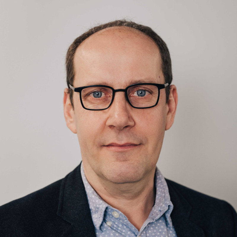 A man in front of a white wall.