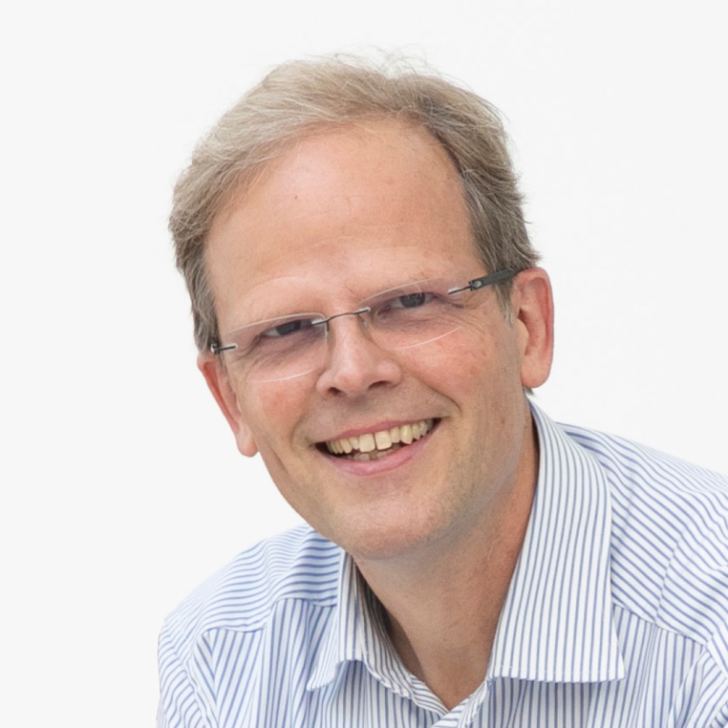 A man in front of a white wall.